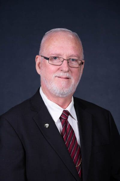 Man in suit with glasses and tie.