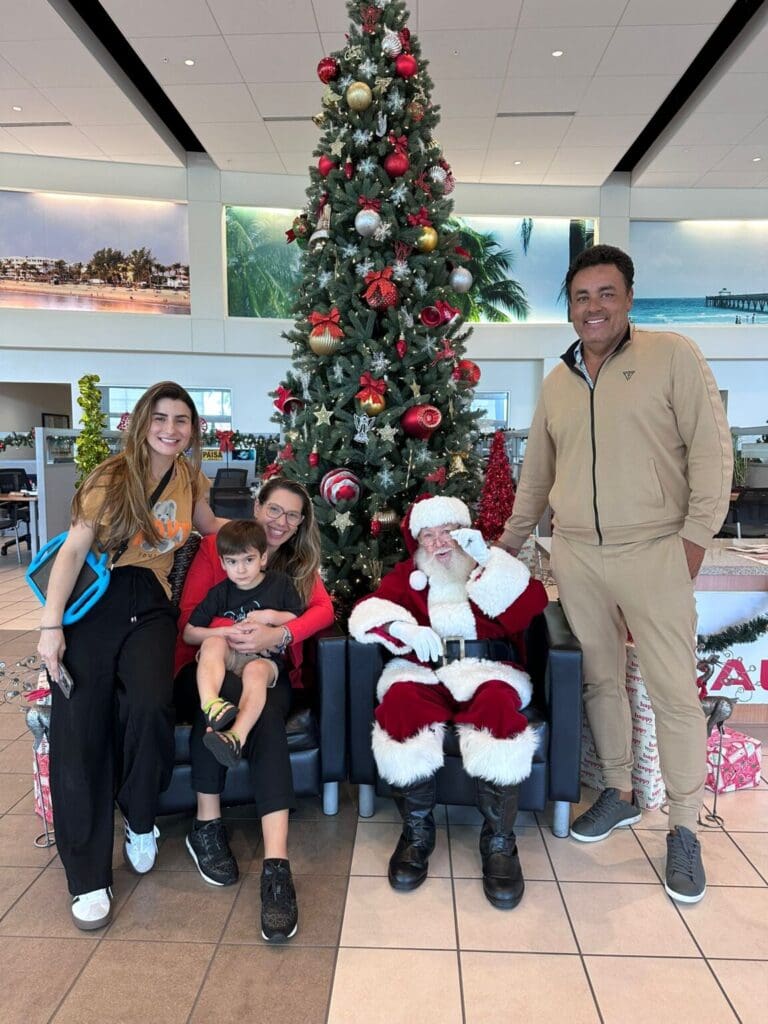 Family posing with Santa Claus in front of a decorated Christmas tree.