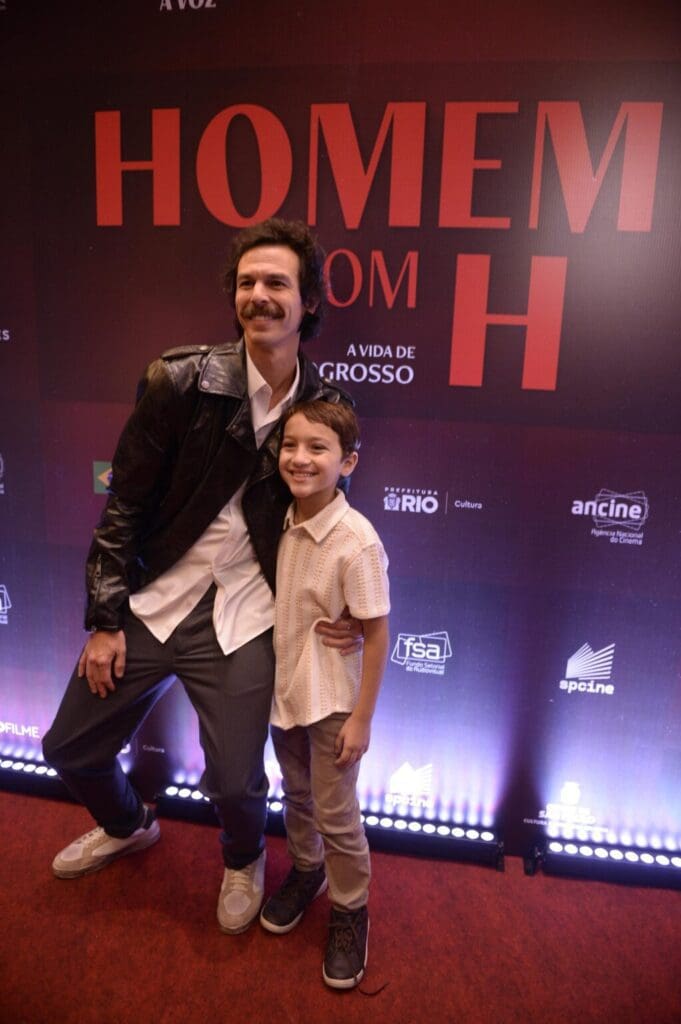 A man and a young boy smiling on a red carpet event.