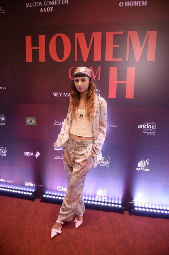 Young woman posing at an event with a stylish outfit and headband.