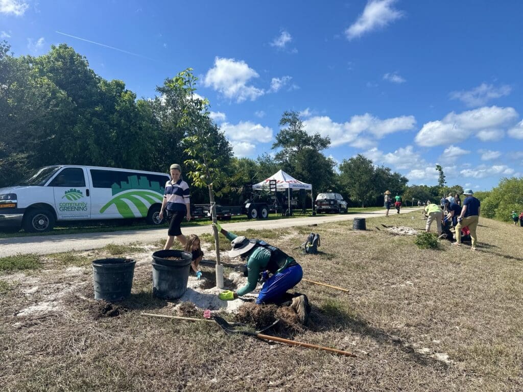 People working outdoors on a sunny day with tools and buckets.