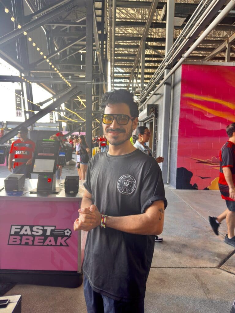 Man wearing sunglasses and a black shirt at an outdoor event.