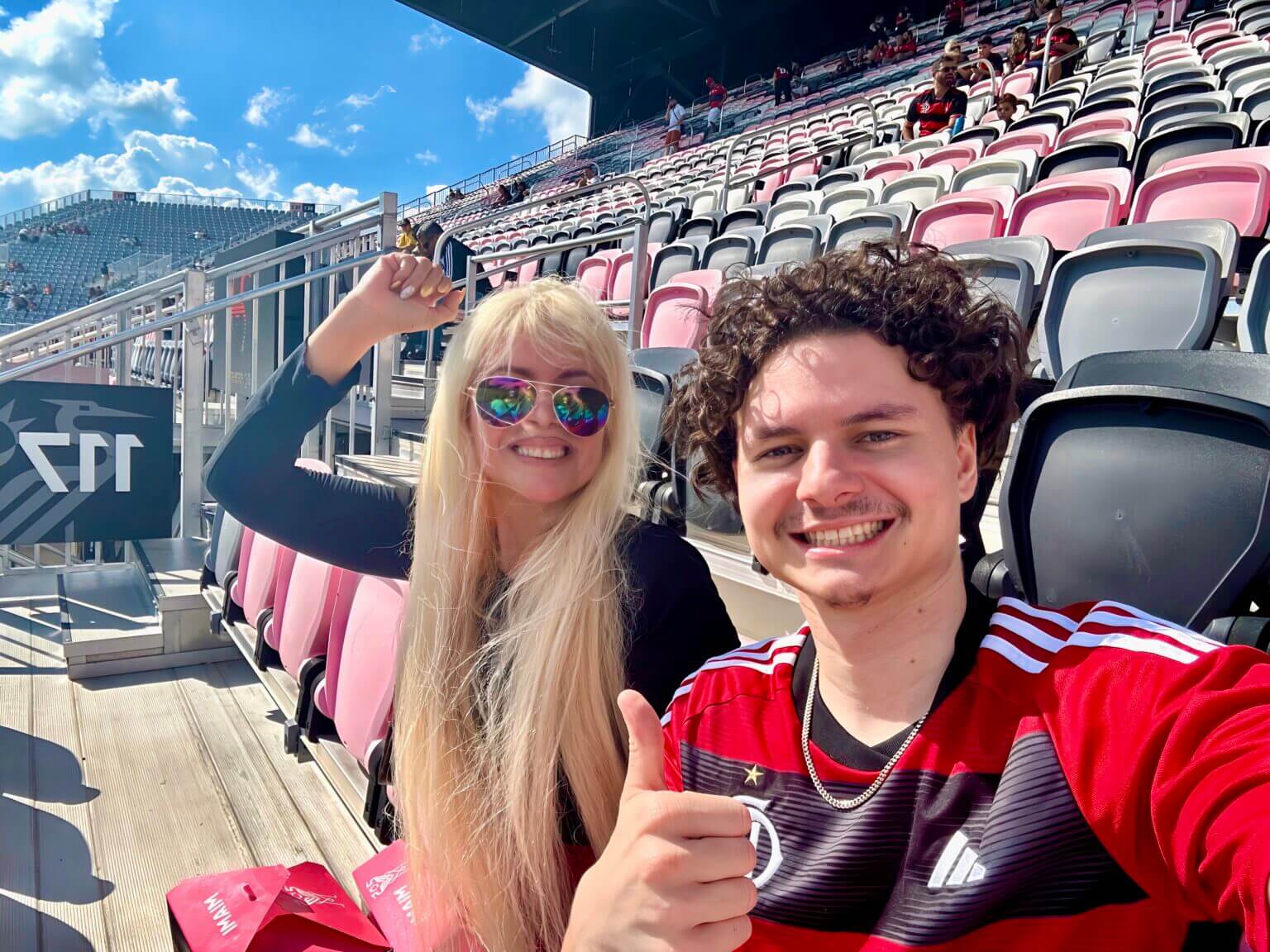 Two young fans smiling and giving thumbs up in a stadium.