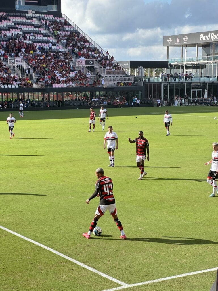 Soccer players in action on a sunny field with a full stadium.
