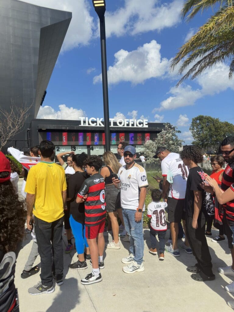 Crowd gathers outside Dick's Donuts on a sunny day.