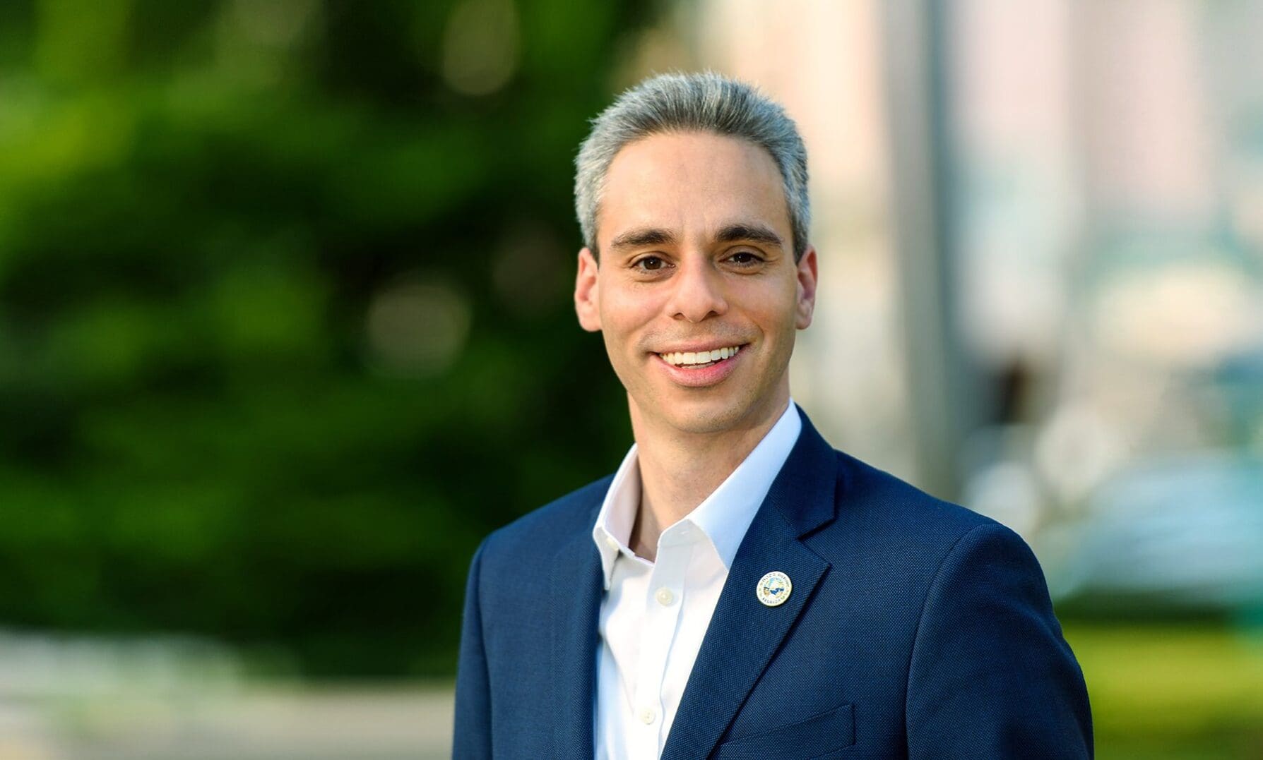 Young man in a blue suit smiling outdoors.