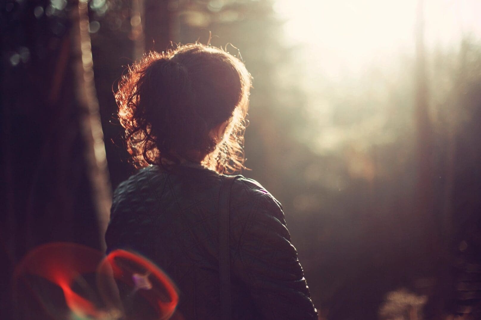 Person in forest, sunlight in background.