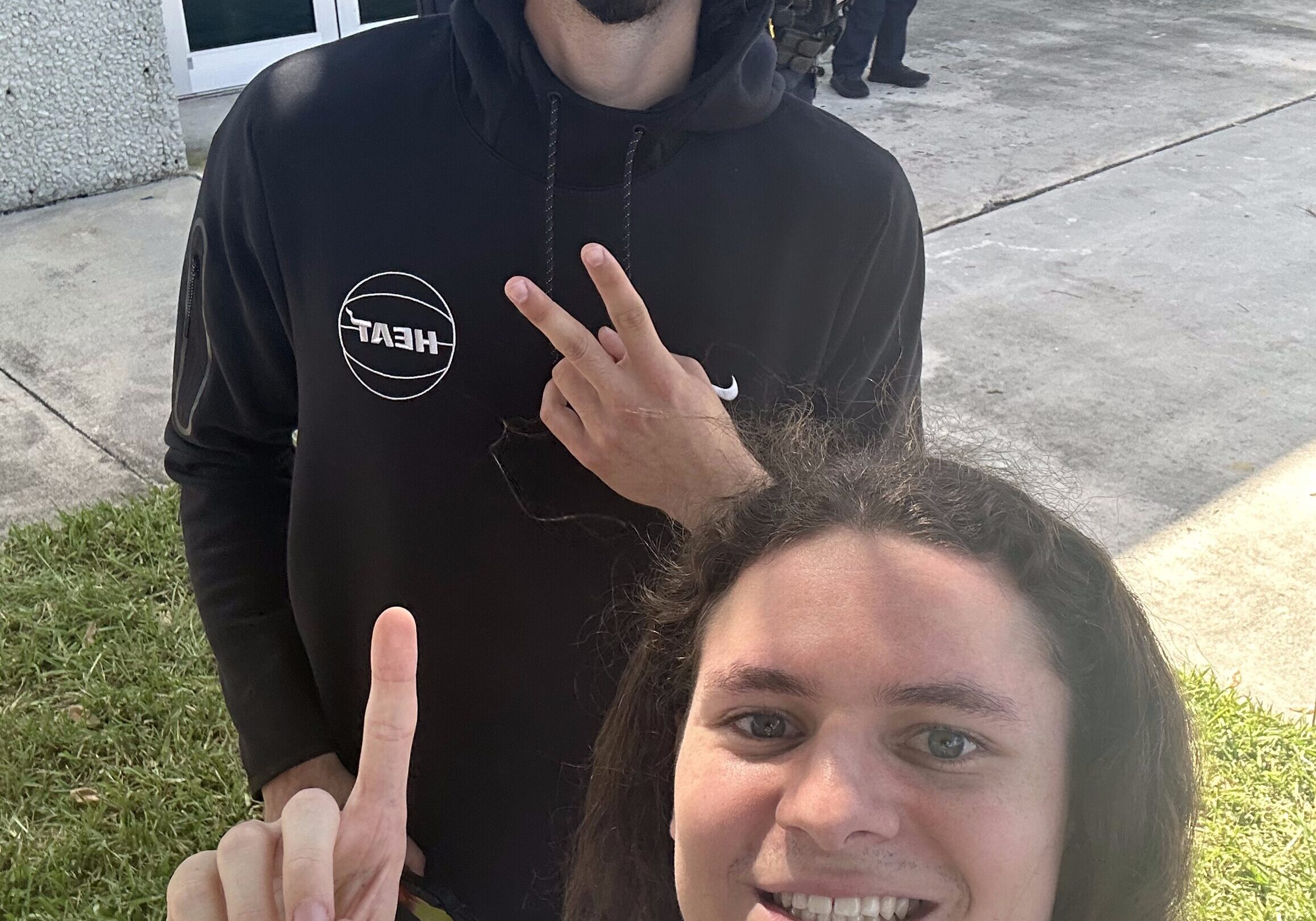 Two people smiling and posing outside building.