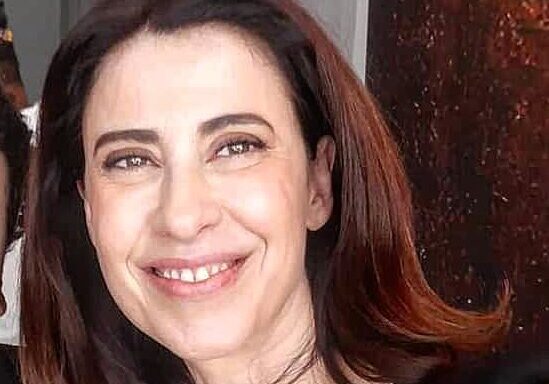 Smiling person with shoulder-length dark hair.